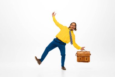 Portrait of stylish man, office worker in bright outfit posing with briefcase isolated over white studio background. Concept of human emotions, office, success, career, expression. Copy space for ad