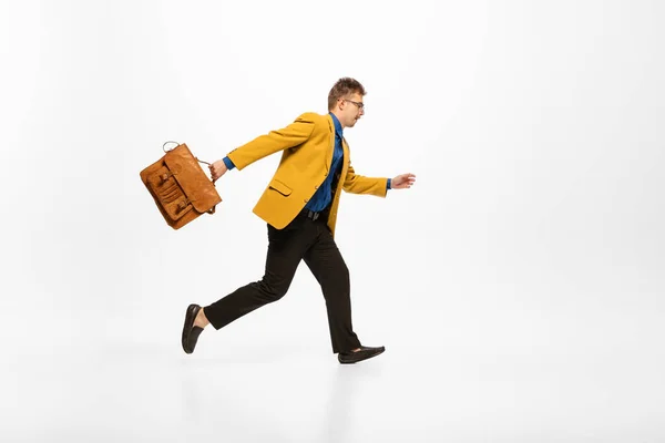 Portrait of man in yellow jacket with vintage briefcase running to work isolated over white background. Concept of human emotions, office, success, career, expression. Copy space for ad