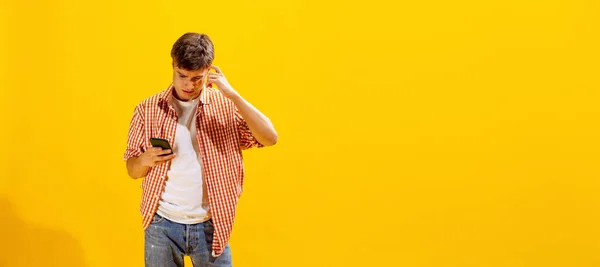 Portrait Young Man Checkered Shirt Posing Looking Phone Curious Expression — Stok fotoğraf