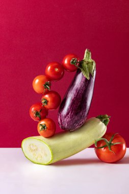 Set of healthy fresh vegetables. Tomatoes, eggplant and vegetable marrow isolated over dark pink background. Healthy eating, dieting. Vitamins. Concept of grocery, nutrition, taste. Colorful image