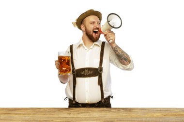 Portrait of man wearing traditional Bavarian or German clothes shouting in megaphone and inviting to beer party isolated on white background. Alcohol, Oktoberfest festival, traditions, taste concept.