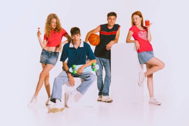 Group of young stylish people, university students posing isolated over grey background. Hobby of youth. Sport, style, elegance. Concept of youth, retro style, 90s era, fashion, lifestyle, ad