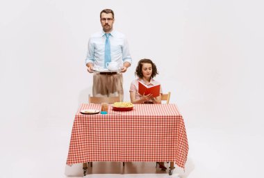 Kahve demliği ve kitap okuyan hassas bir kadının portresi. Beyaz arka planda kahvaltı yapan bir aile. Aşk kavramı, ilişki, eski tarz, yaratıcılık. İlan için alanı kopyala