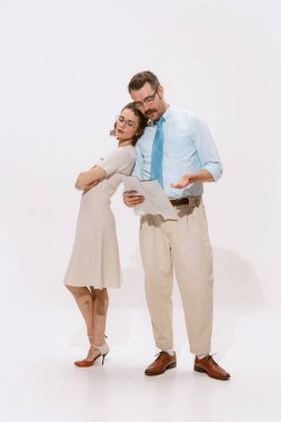 Çift portresi, evrak okuyan bir adam ve beyaz arka planda yalnız başına omzuna yaslanan bir kadın. Aşk kavramı, ilişki, eski tarz, yaratıcılık, aile. İlan için alanı kopyala