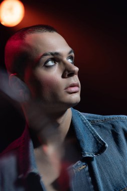 Makyaj yapan genç adamın yakın plan portresi, dumanlı gözler, yanaklarda kızarıklık, neon ışıkta izole edilmiş bir şekilde poz verme. Moda kavramı, seçim özgürlüğü, yaşam tarzı, lgbt, Z nesli