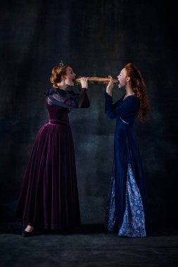 Siyah arka planda izole edilmiş dev sandviçleri yiyen kraliçelerin portresi. Devir, modernlik ve rönesans kavramı, barok tarzı, güzellik, tarih