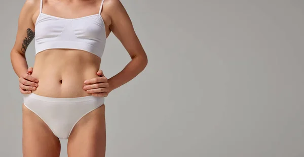 Cropped image os muscular female body in underwear, belly isolated on grey studio background. Body shaping. Concept of beauty, body and skin care, health, plastic surgery, cosmetics. Copy space for ad