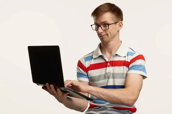 ノートパソコンを装ったメガネ姿の青年の肖像画は 白いスタジオを背景にオンラインで作品を孤立させている ライフスタイル 若者の概念 広告のコピースペース — ストック写真