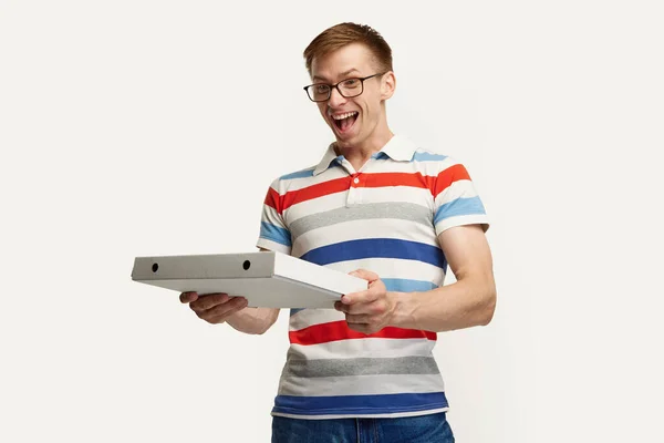 白いスタジオの背景にピザの配達を得る眼鏡の若い男の肖像画 快適なオンラインショッピング ライフスタイル 若者の概念 広告のコピースペース — ストック写真