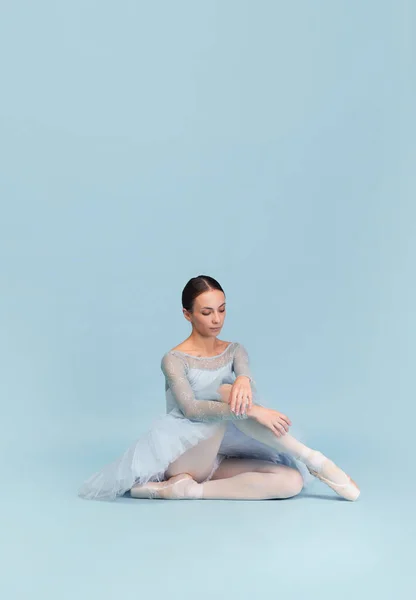 轻柔的年轻芭蕾舞演员的肖像 在蓝色的工作室背景上独立表演 冷静地坐着经典芭蕾的概念 创造力 — 图库照片