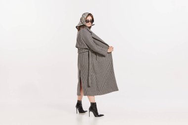 Beyaz arka planda izole edilmiş, ceketli ve güneş gözlüklü şık genç bir kadının portresi. Sırları açıyorum. Retro moda kavramı, tarz, yaratıcılık, gençlik kültürü, duygular, reklam