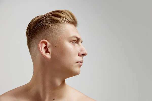 Portrait of young man posing shirtless isolated over grey studio background. Looking right side. Concept of mens health, natural beauty, body and skin care, male cosmetology, plastic surgery