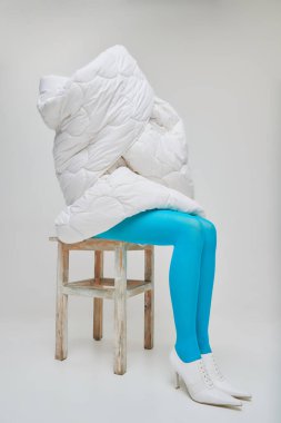 Gri stüdyo arka planında izole edilmiş battaniyeyle kaplı mavi taytlı genç kız portresi. Depresyon. Eski moda kavramı, sanat fotoğrafçılığı, stil, nonoş, güzellik, reklam.