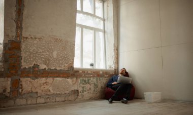 Bir iş adamı büyük bir odanın köşesinde dizüstü bilgisayarlı ve çalışıyor. İş kapandı. Profesyonel kriz. İş kavramı, zorluklar, iş, meslek