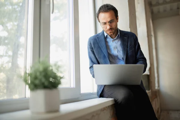 Retrato Jovem Empresário Sentado Janela Com Laptop Trabalhando Com Expressão — Fotografia de Stock