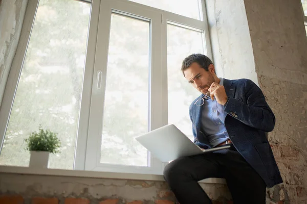 Retrato Jovem Empresário Sentado Janela Com Laptop Trabalhando Com Expressão — Fotografia de Stock