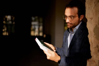 Duvarda boş bir odada elinde defterle duran iş adamının portresi. Yeni bir iş açmak için profesyonel analizler ve sayımlar yapıyor. İş kavramı, zorluklar, iş, meslek