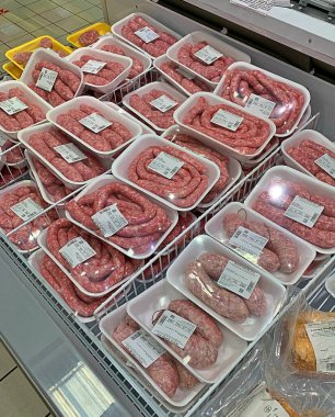 Italian raw sausages prepared in plastic trays and covered with foil, Italian sausages in the store, raw sausages in store refrigerators