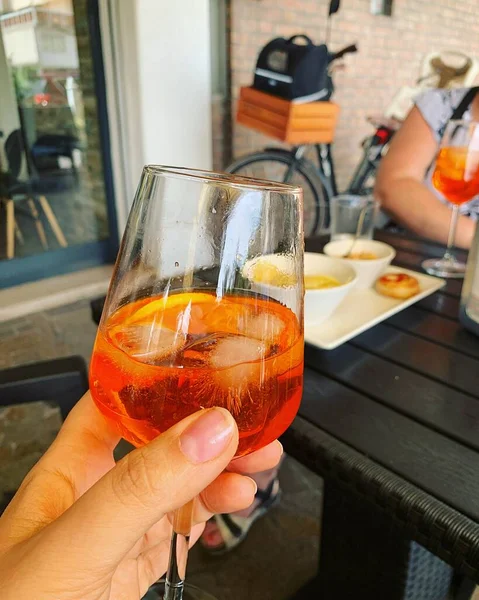 having a drink in a caf, orange spritz, glass with spritz and ice cubes, relaxing with a drink, Italian drink with a bitter taste