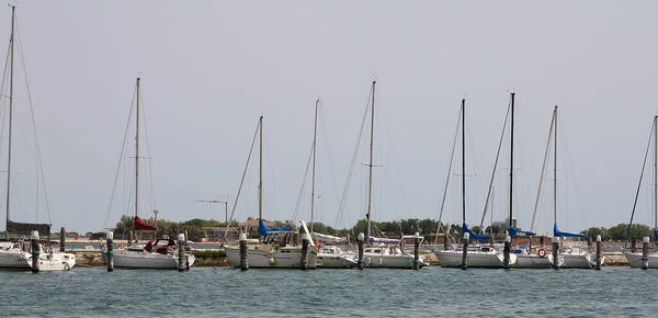 a row of boats moored, many boats along the coast, white ships, calm sea, Chioggia area, Italy