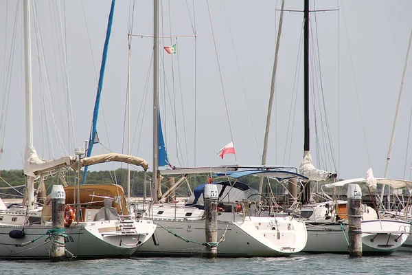 moored in a row of boats, many boats along the coast, white ships, calm sea, Chioggia area, Italy, Polish flag, white and red flag