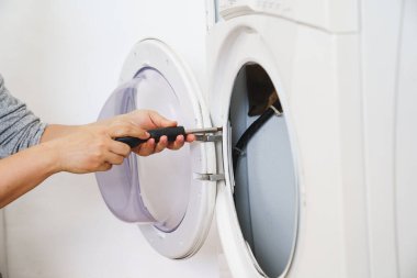 Tamirci çamaşır makinesini tamir eder, parçalara ayırır.
