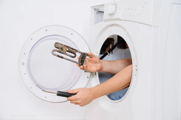 Repair of washing machine. in hand old tubular electric heater — Stock Photo, Image