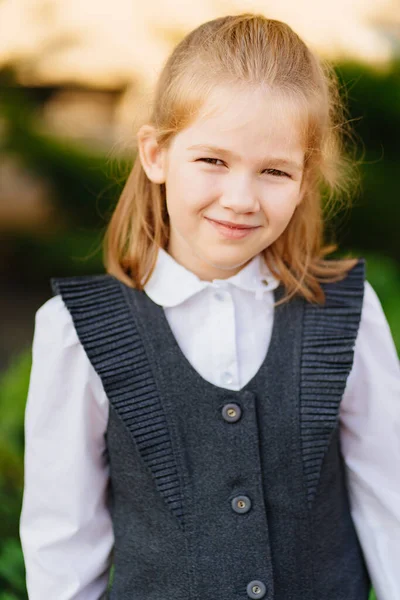 En söt tjej i grå skoluniform. Försäljning av kläder för skolbarn. — Stockfoto