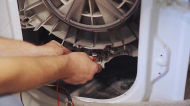 Tamirci çamaşır makinesini tamir eder, bir tankı imha eder.