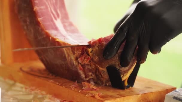 Un hombre con guantes corta en trozos finos de carne seca para un banquete. — Vídeos de Stock