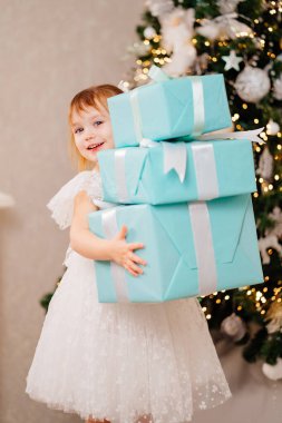 Noel ağacında elinde hediyelerle beyaz elbiseli mutlu bir kız.. 