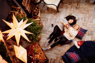 Üst Manzara. Yeni yıl süslemelerinde şöminede neşeli kız arkadaşlar