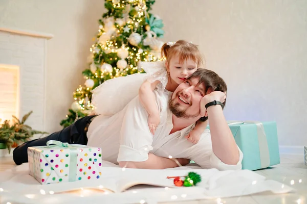 Ο μπαμπάς και η μικρή κόρη γράφουν ένα γράμμα στον Άγιο Βασίλη κάτω από το χριστουγεννιάτικο δέντρο.. — Φωτογραφία Αρχείου