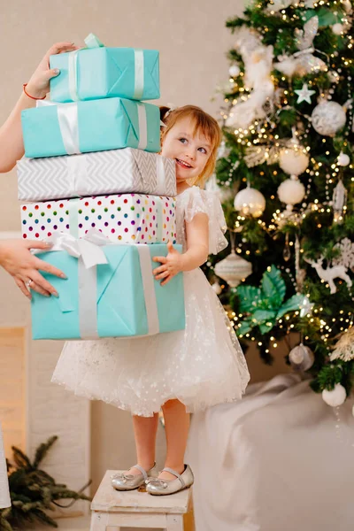 Noel ağacında elinde hediyelerle beyaz elbiseli mutlu bir kız.. 