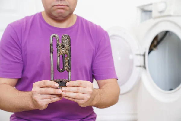 Reparador de lavadora sostiene viejo calentador eléctrico tubular — Foto de Stock
