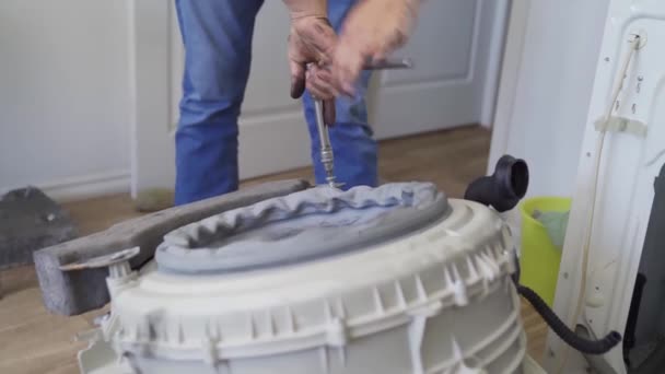 Reparatören reparerar tvättmaskinen, tar fram en tank — Stockvideo