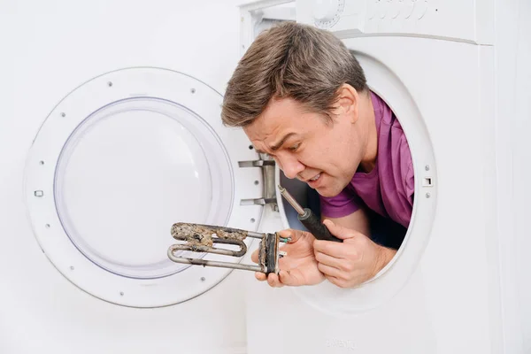 Reparador de lavadora sostiene calentador eléctrico tubular y destornillador — Foto de Stock