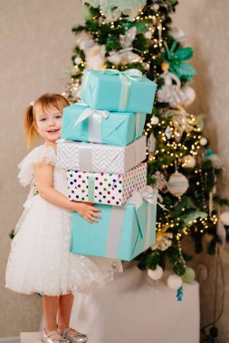 Noel ağacında elinde hediyelerle beyaz elbiseli mutlu bir kız.. 