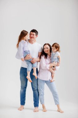 Beyaz bir fotoğraf stüdyosundaki fotoğraf çekiminde güzel, mutlu bir aile. sahne arkası.