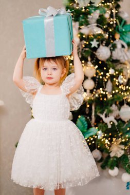 Beyaz elbiseli mutlu bir kız Noel ağacında kafasına hediye almış.. 