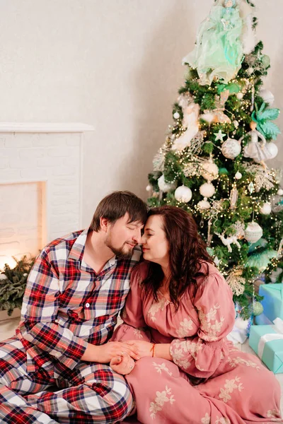 在圣诞树旁，男人和女人坠入爱河，快乐无比. — 图库照片