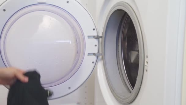 Жінка кладе брудний одяг в пральну машину і капсулу . — стокове відео