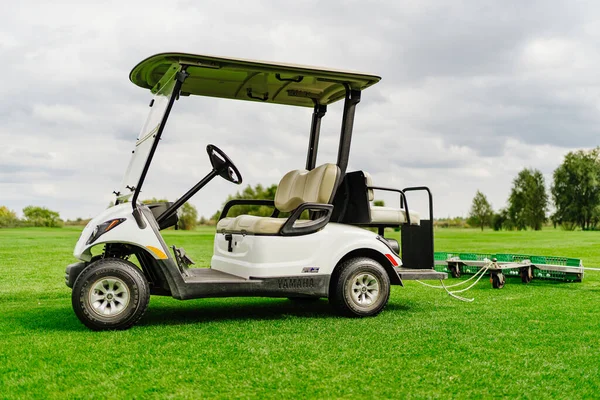 Um carro eléctrico com um reboque para recolher bolas no campo de golfe. — Fotografia de Stock