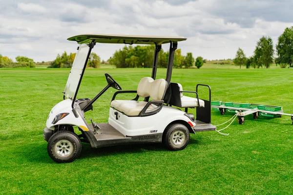 Samochód elektryczny z przyczepą do zbierania piłek na polu golfowym. — Zdjęcie stockowe
