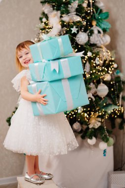 Noel ağacında elinde hediyelerle beyaz elbiseli mutlu bir kız.. 