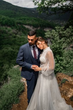 Dağlarda bir düğün töreninde yeni evlilere sarılan güzel bir çift.