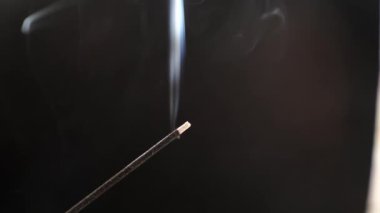 Siyah arka planda aromatik bir çubuktan çıkan duman..