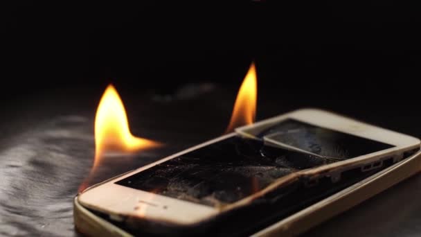 Сжигание сломанного смартфона на черном фоне. — стоковое видео