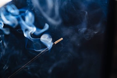 Siyah arka planda aromatik bir çubuktan çıkan duman..