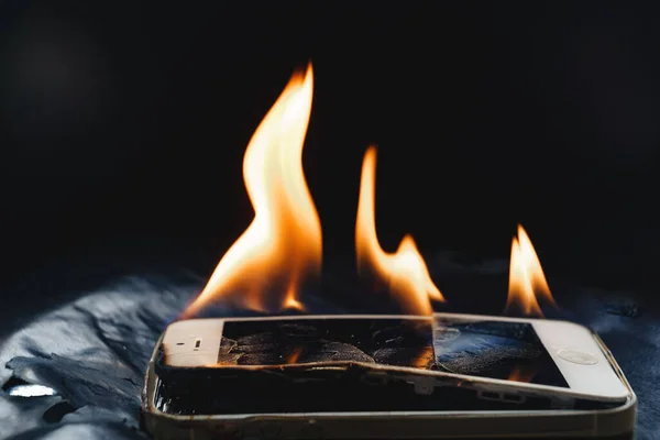 Quemar el teléfono inteligente roto sobre un fondo negro. —  Fotos de Stock